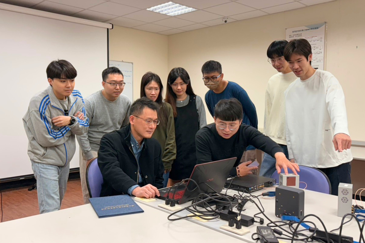 Research team discussing the development and testing of the RIS-enabled smart communication system, which is designed to improve wireless signal coverage and connection stability in complex environments.